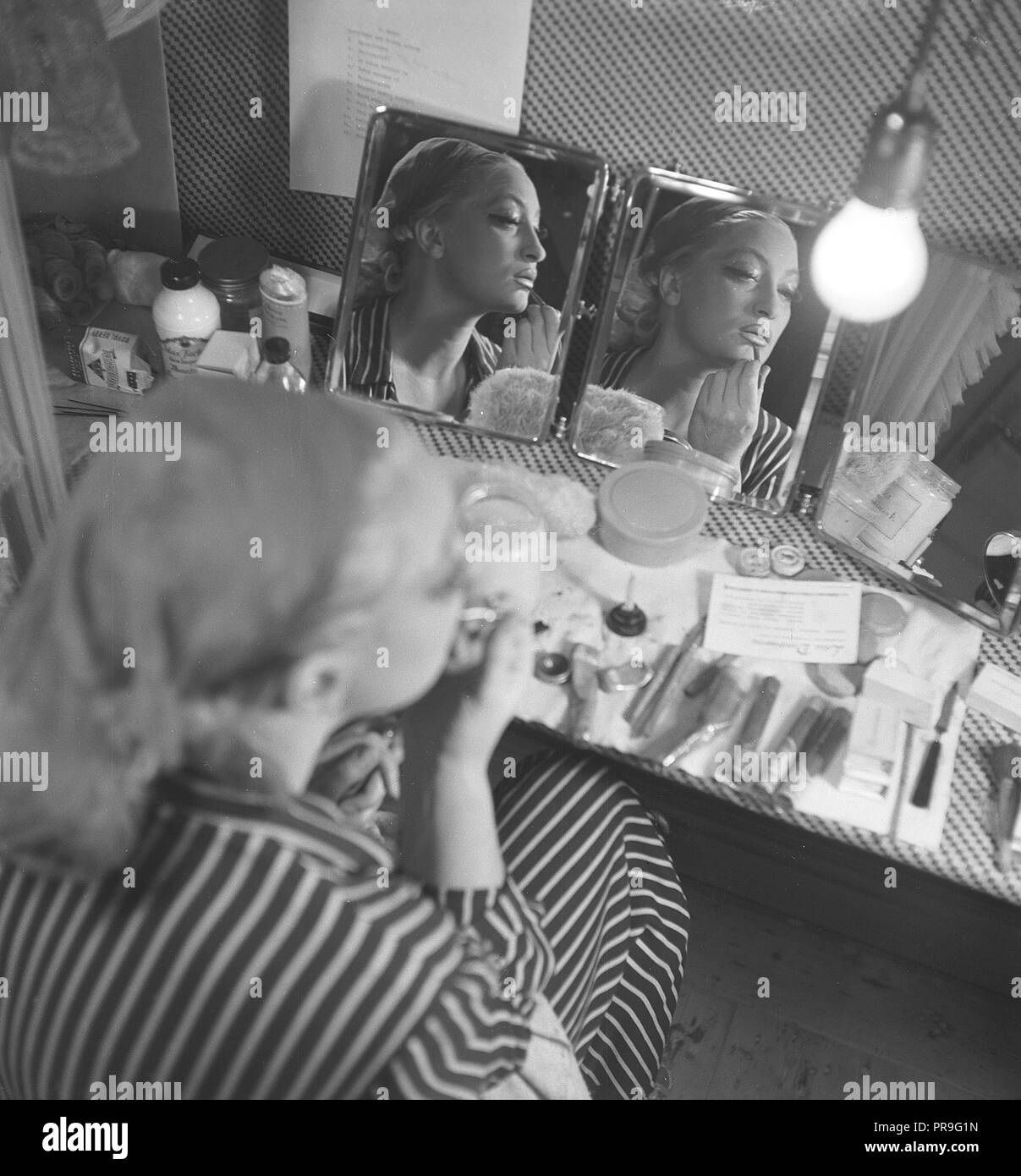 Prodotti cosmetici nel 1940s. Una giovane donna in casa è seduto a un make up desk e guardando se stessa in specchi da angoli diffente pur mettendo su trucco. Ci sono molti tipi differenti di cosmectics giacente sul tavolo di fronte a lei. La Svezia 1944. Foto Kristoffersson AB3-8 Foto Stock