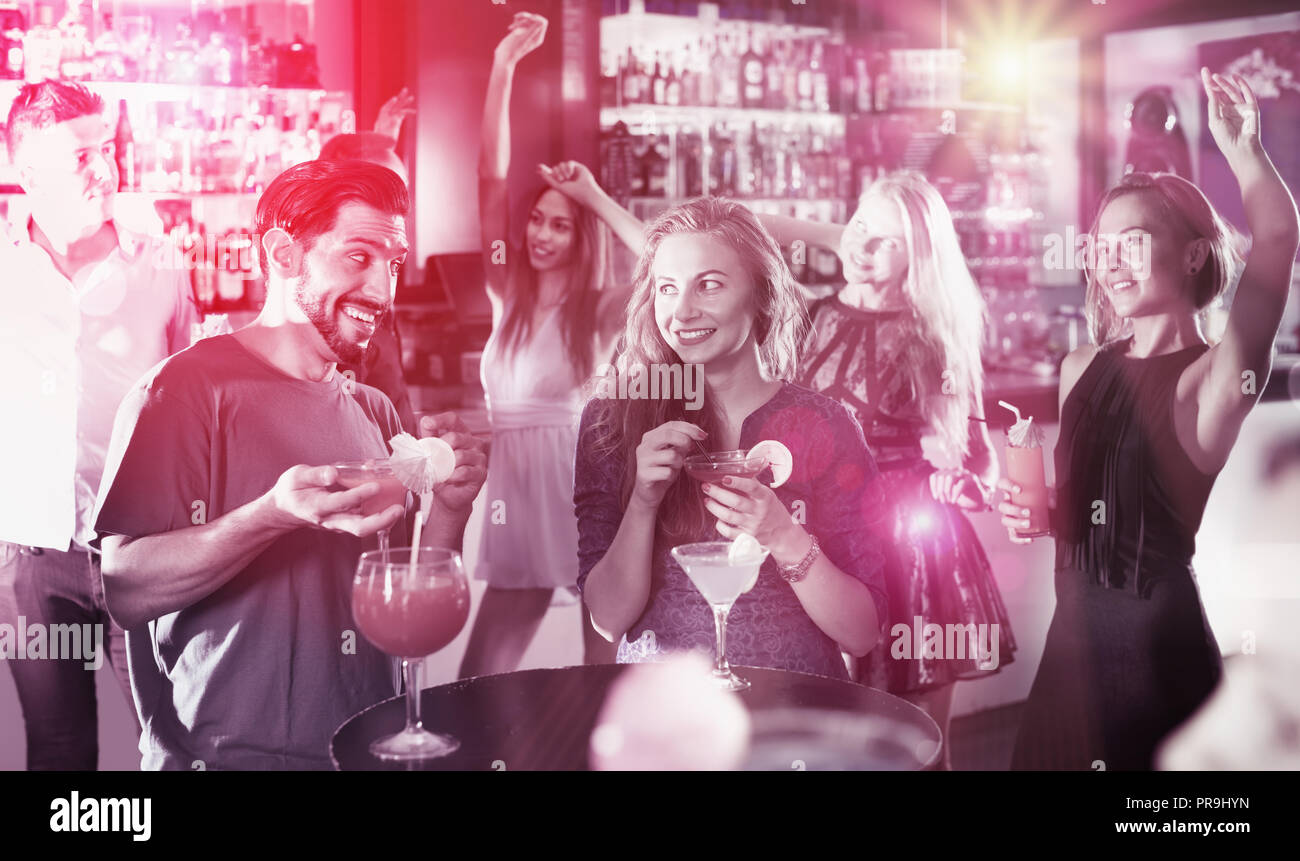 Soddisfatto maschio con femmina sono a parlare e a bere un cocktail sulla parte in club Foto Stock