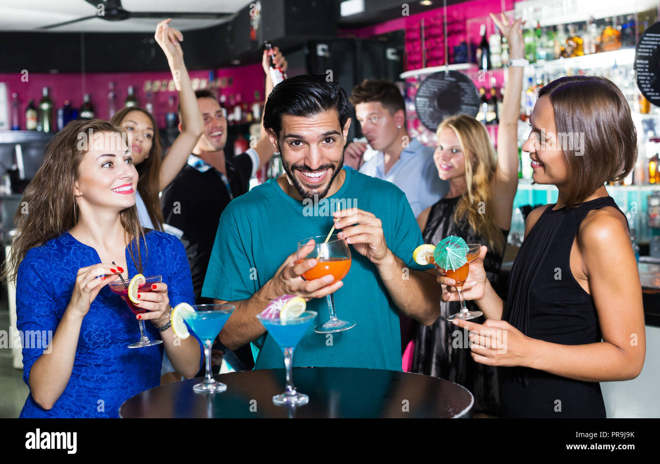 Maschio adulto con due donne stanno parlando e bevendo un cocktail sulla parte. Foto Stock
