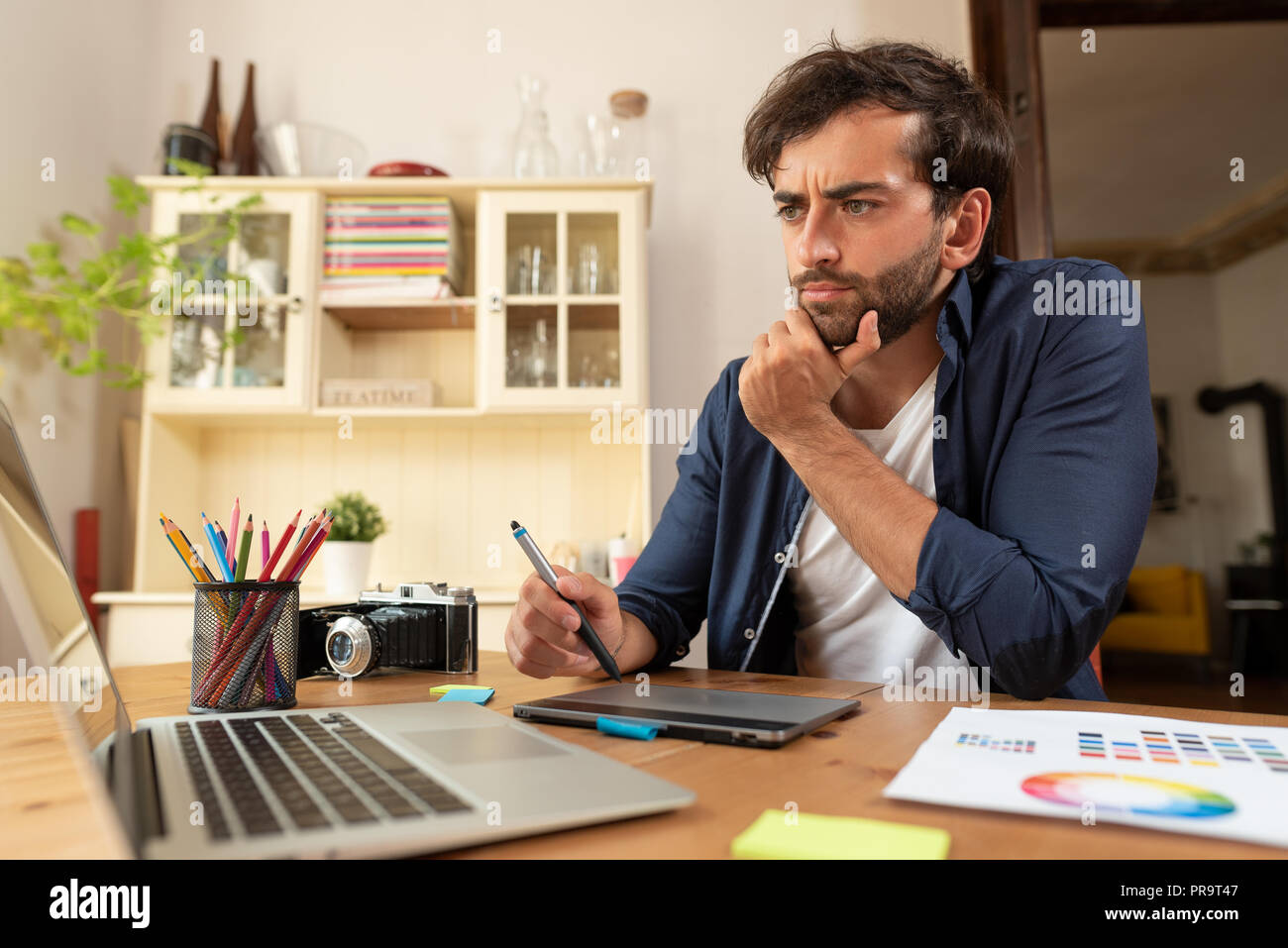 Graphic designer che lavora sulla tavoletta digitale. Libero professionista a lavorare a casa. Foto Stock