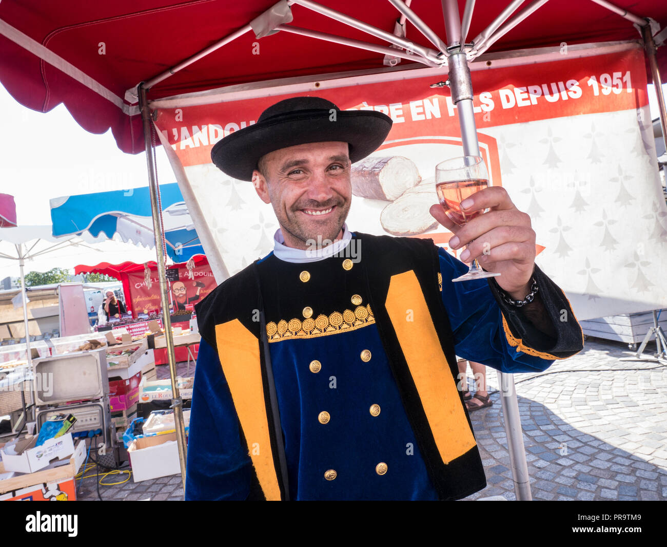 CONCARNEAU felice di stallo del mercato francese porta l uomo nella tipica tradizionale costume bretone dicendo cheers con vetro francesi di vino rosato Foto Stock
