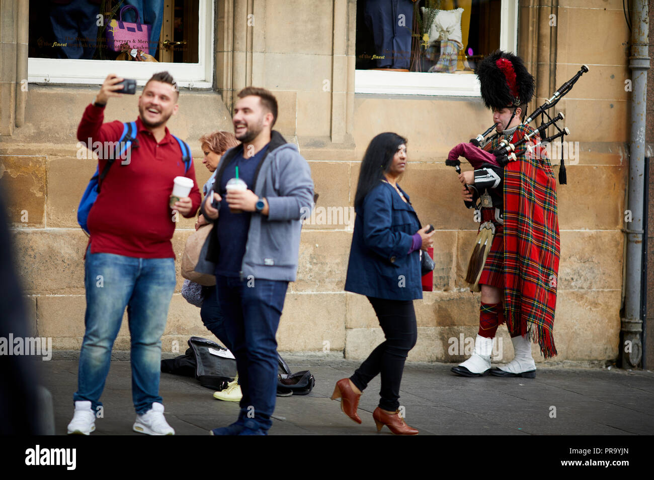 Street performance busker ai turisti di Edimburgo, Scozia, Canongate Royal Mile un vestito tradizionale piper suonare la cornamusa per denaro Foto Stock