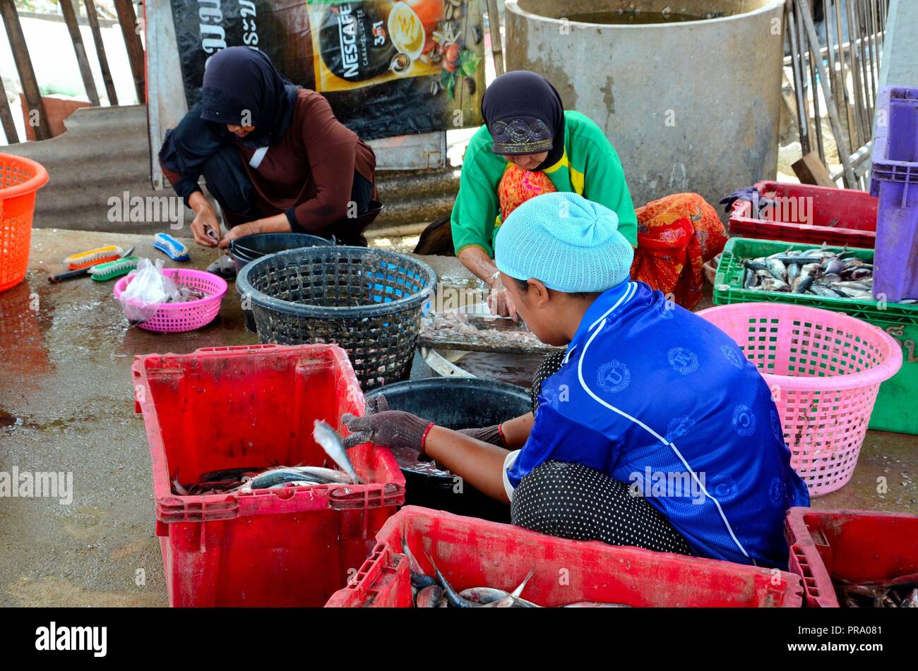 Tre Tailandese donne hijab come pulire e lavare il pesce a villaggio in Pattani Thailandia Foto Stock