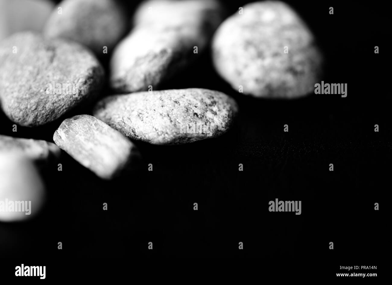 Pietre sparse su uno sfondo scuro vicino. In bianco e nero Foto Stock