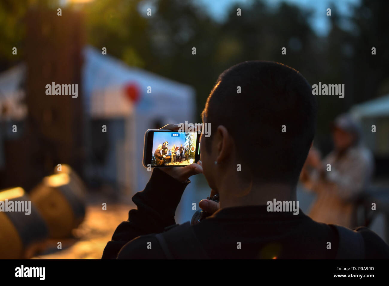 Giovane uomo asiatico facendo una registrazione video di un concerto live show sul suo smartphone Foto Stock