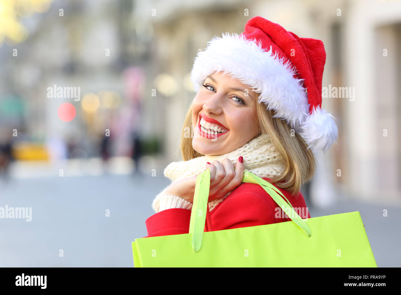 Ritratto di una donna felice weating una santa claus hat shopping a Natale ti guarda all'aperto sulla strada Foto Stock