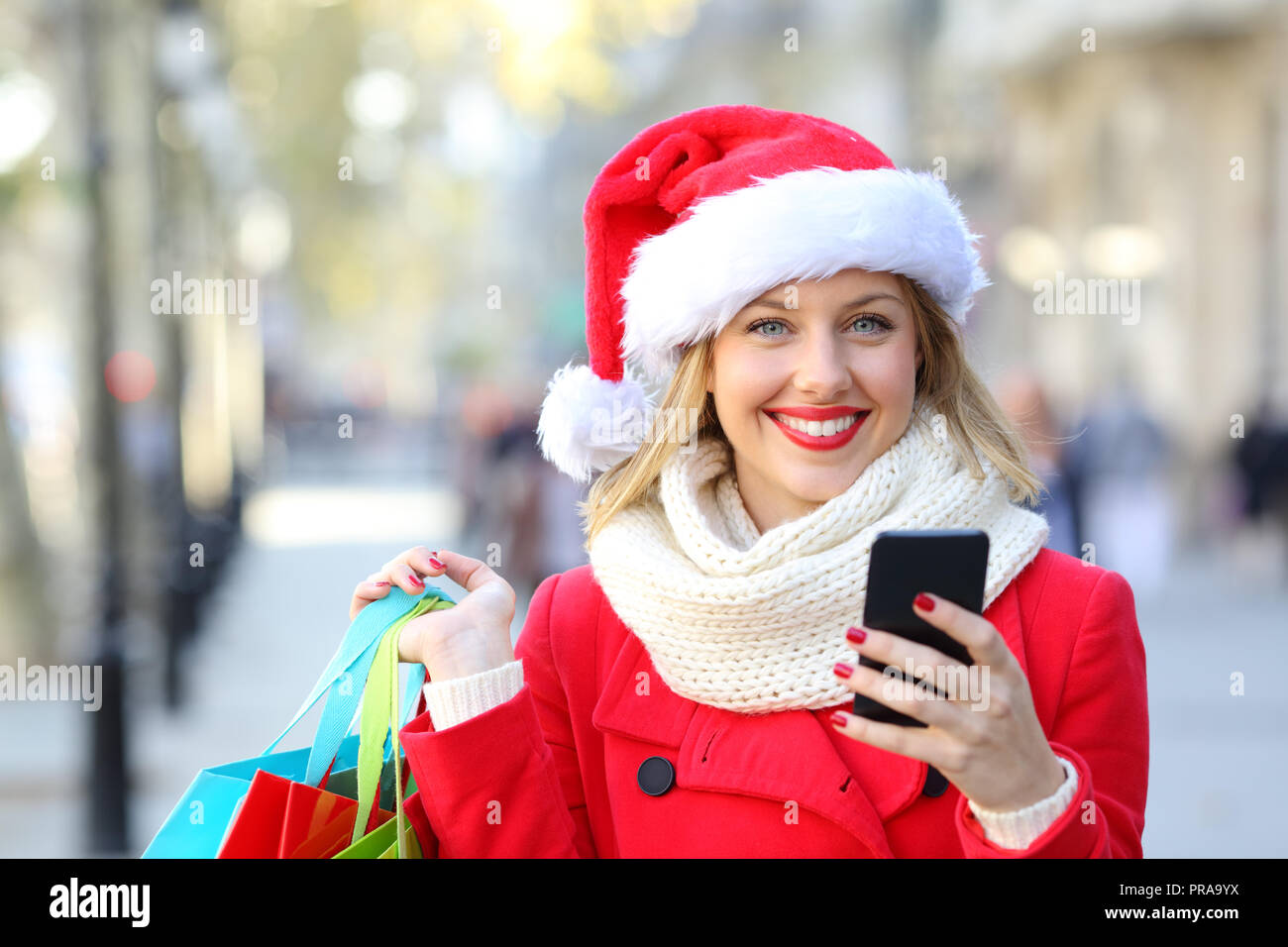 Vista anteriore verticale di un felice shopper shopping online guardando la fotocamera su vacanze di Natale sulla strada Foto Stock