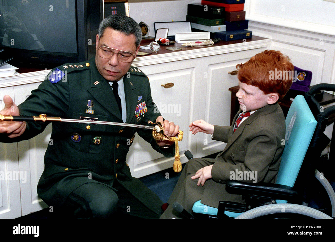 Stati Uniti Army General Colin Powell, Presidente del Comune di capi di Stato Maggiore, posa per una foto con lancia E. Fallon (in sedia a rotelle), il bambino Poster per l'associazione di distrofia muscolare, al Pentagono a Washington, D.C., Marzo 24, 1993. Foto Stock