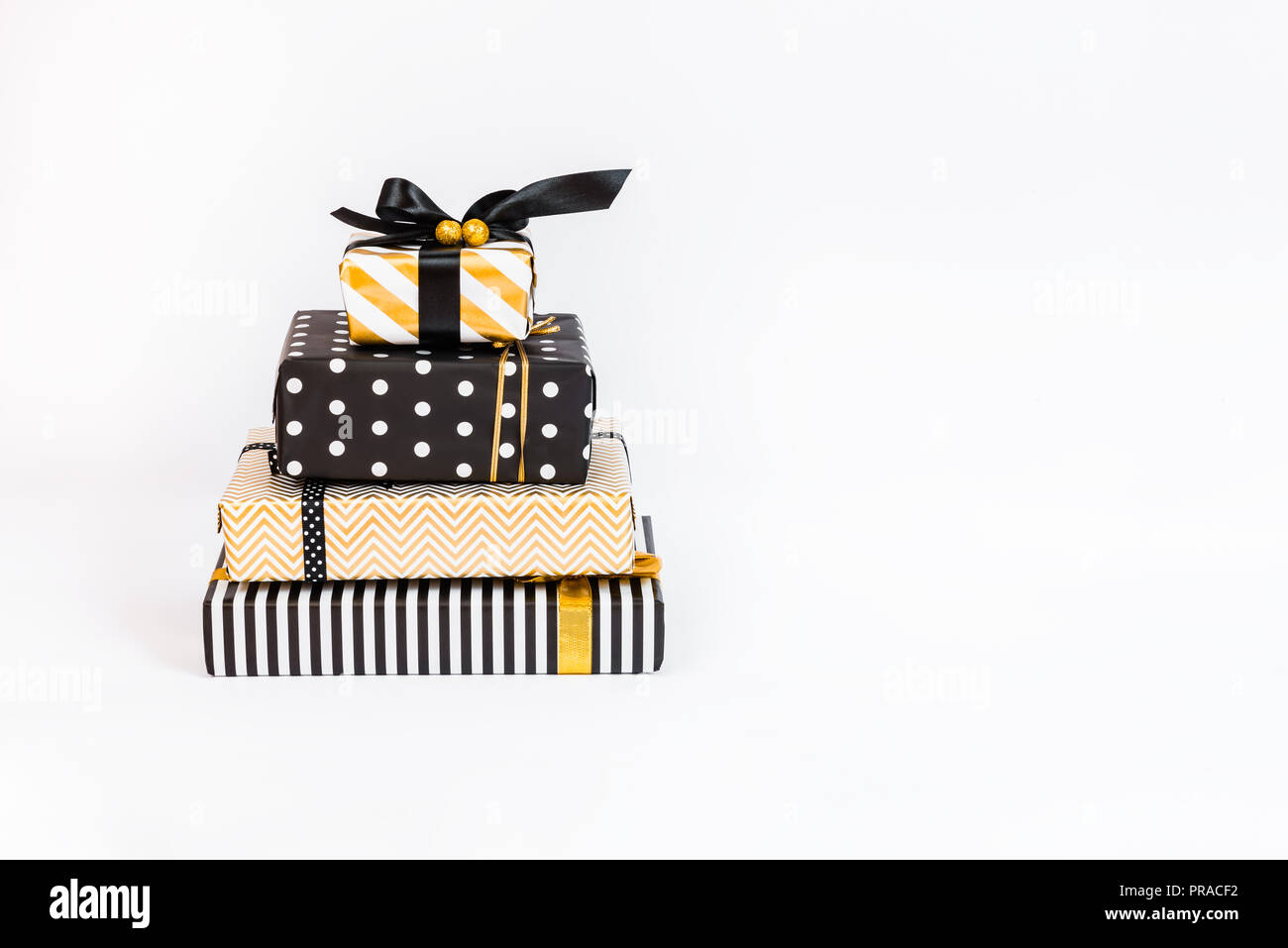 Un mucchio di scatole regalo in vari nero, bianco e disegni dorati disposti come strati di una torta di compleanno. Un concetto di Natale, Capodanno, compleanno ce Foto Stock