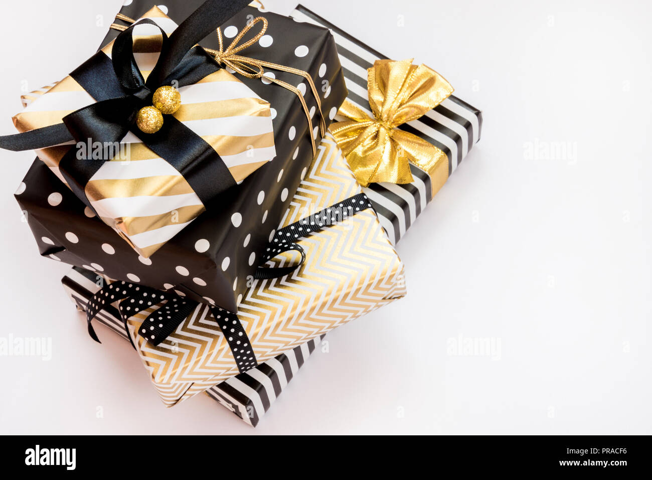 Vista dall'alto di un mucchio di scatole regalo in vari nero, bianco e disegni dorati. Un concetto di Natale, Capodanno, Festa di compleanno evento. Foto Stock