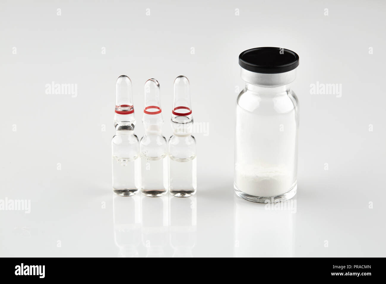 Piccola bottiglia sigillata con la medicina e le fiale su sfondo bianco. Foto Stock