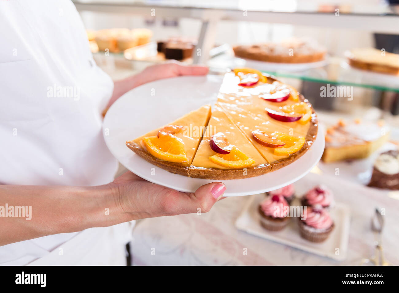 Baker donna vendita mettendo torte che sul display Foto Stock