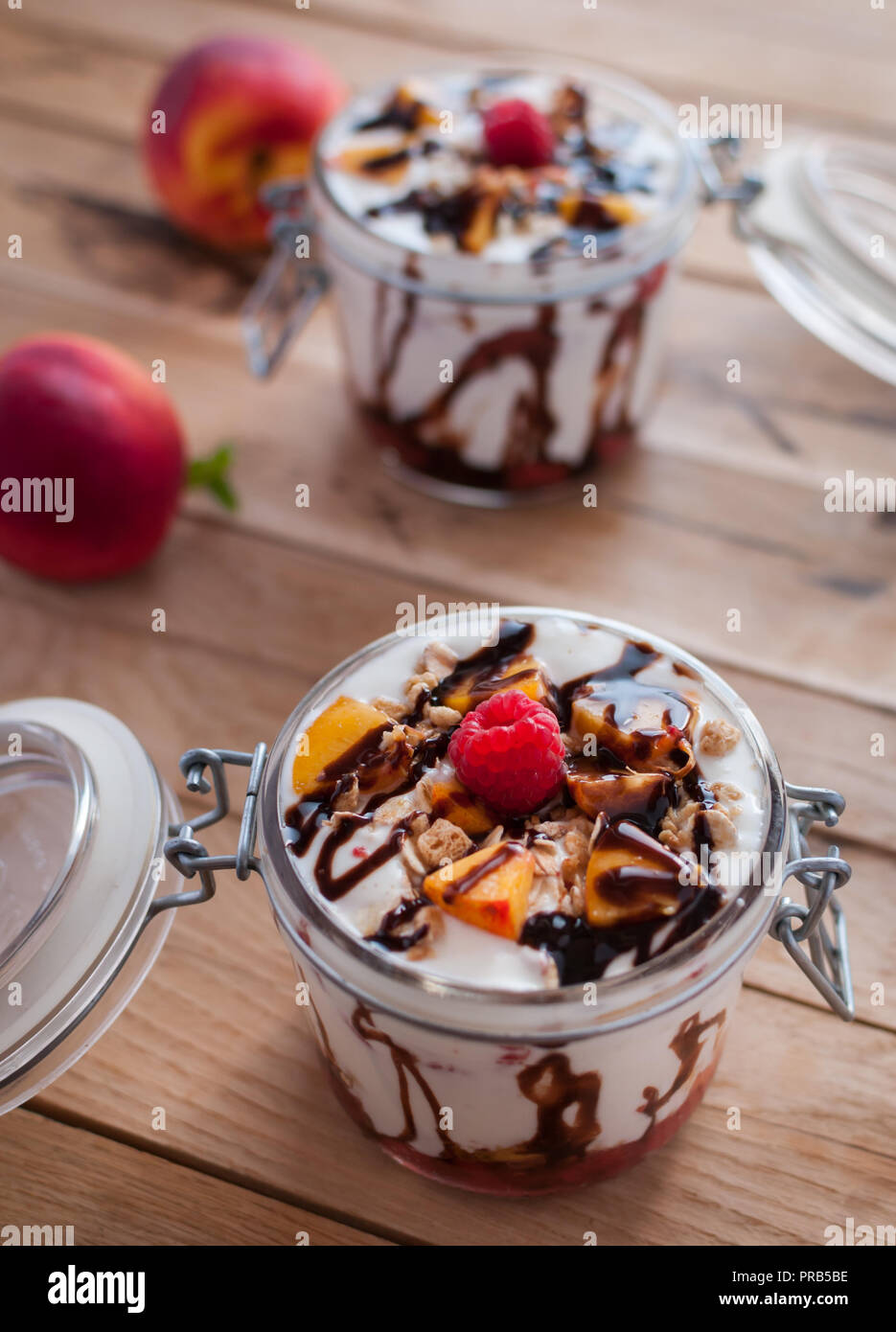 Close-up di parfait di pesche con yogurt, muesli e topping di cioccolato in un vaso Foto Stock