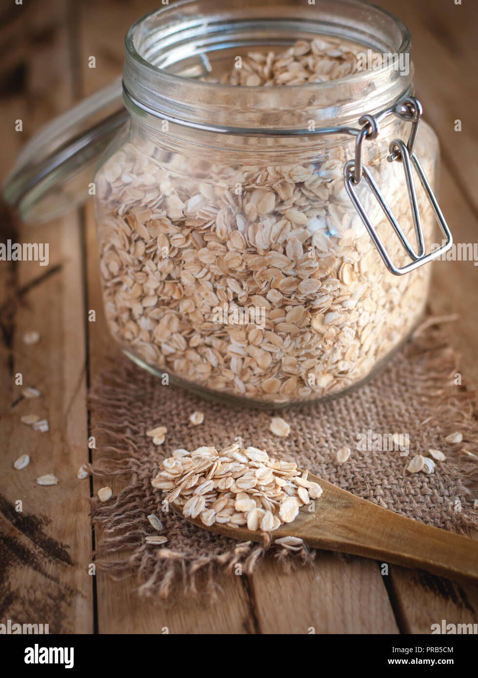 Avena in un cucchiaio di legno e in un vaso, su sfondo di legno Foto Stock