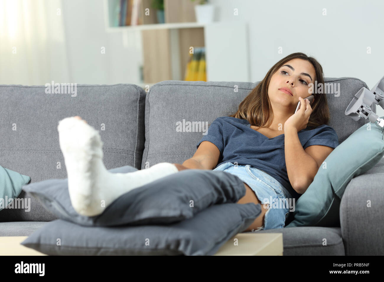 Disabili gravi Donna che parla al telefono seduto su un divano nel salotto di casa Foto Stock