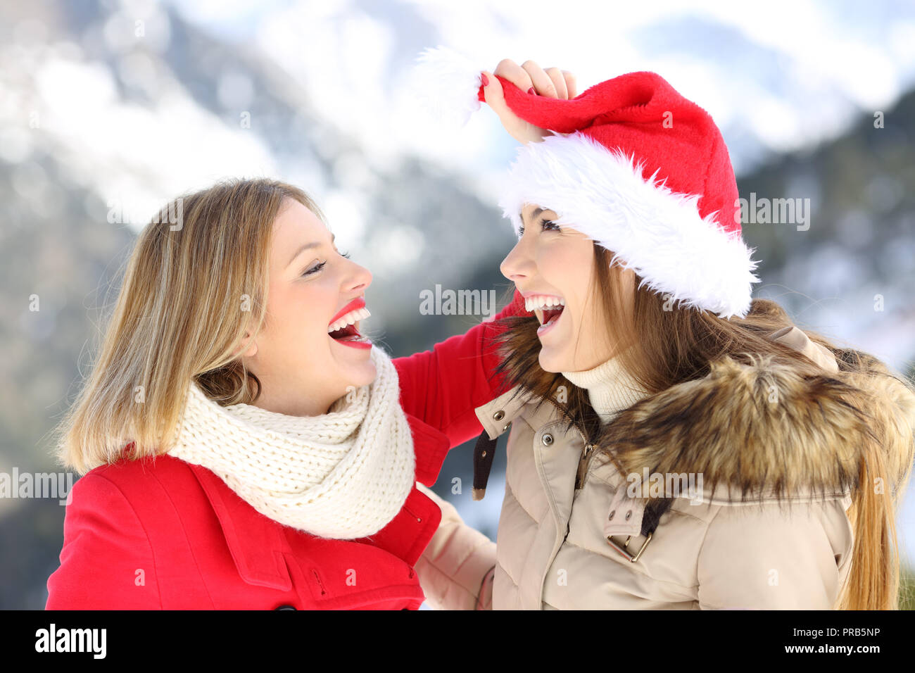 Due happy amici scherzando sulle vacanze di Natale con una montagna innevata in background Foto Stock