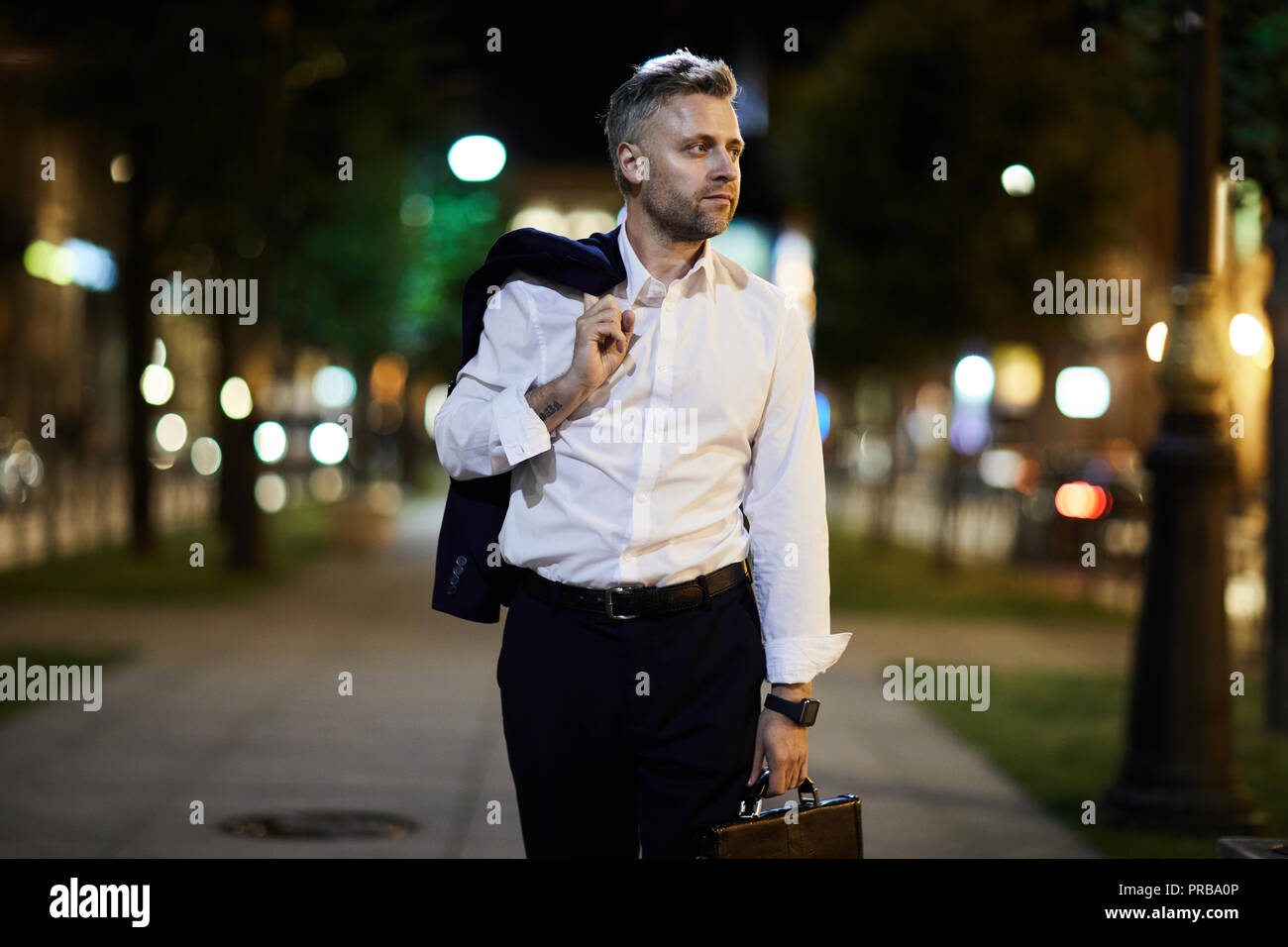 Imprenditore stanco di tornare a casa dopo una lunga giornata di lavoro di sera Foto Stock