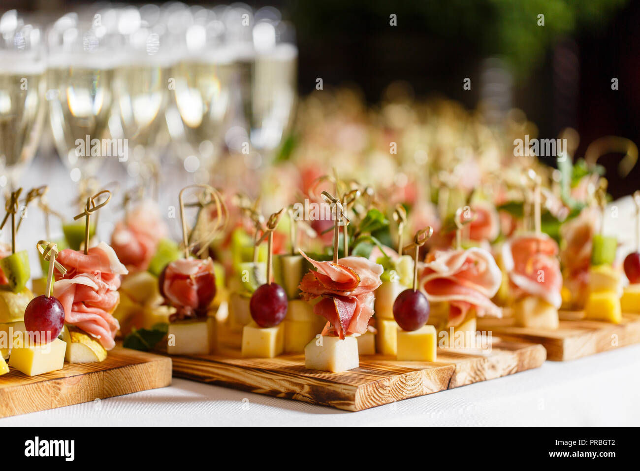 Il buffet presso la reception. Bicchieri di vino e champagne. Assortimento  di tartine sulla tavola di legno. Servizio banchetti. catering food, snack  al formaggio, prosciutto, prosciutto e frutta Foto stock - Alamy