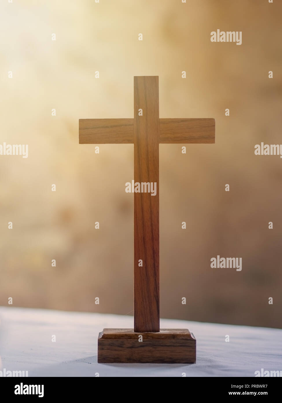 Croce di legno su bianco altare panno, raggi di luce in background. La fede cristiana. Foto Stock