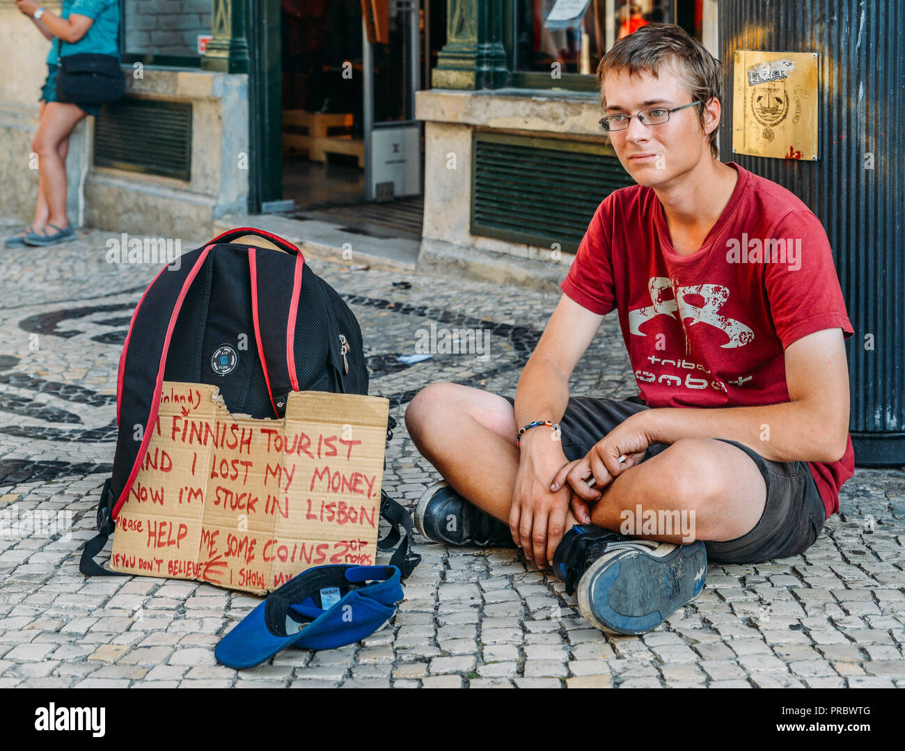 Il finlandese turistico con sob storia scritta sul segno di cartone su nessun denaro, etc mendica per soldi per tornare a casa, Lisbona, Portogallo. Foto Stock