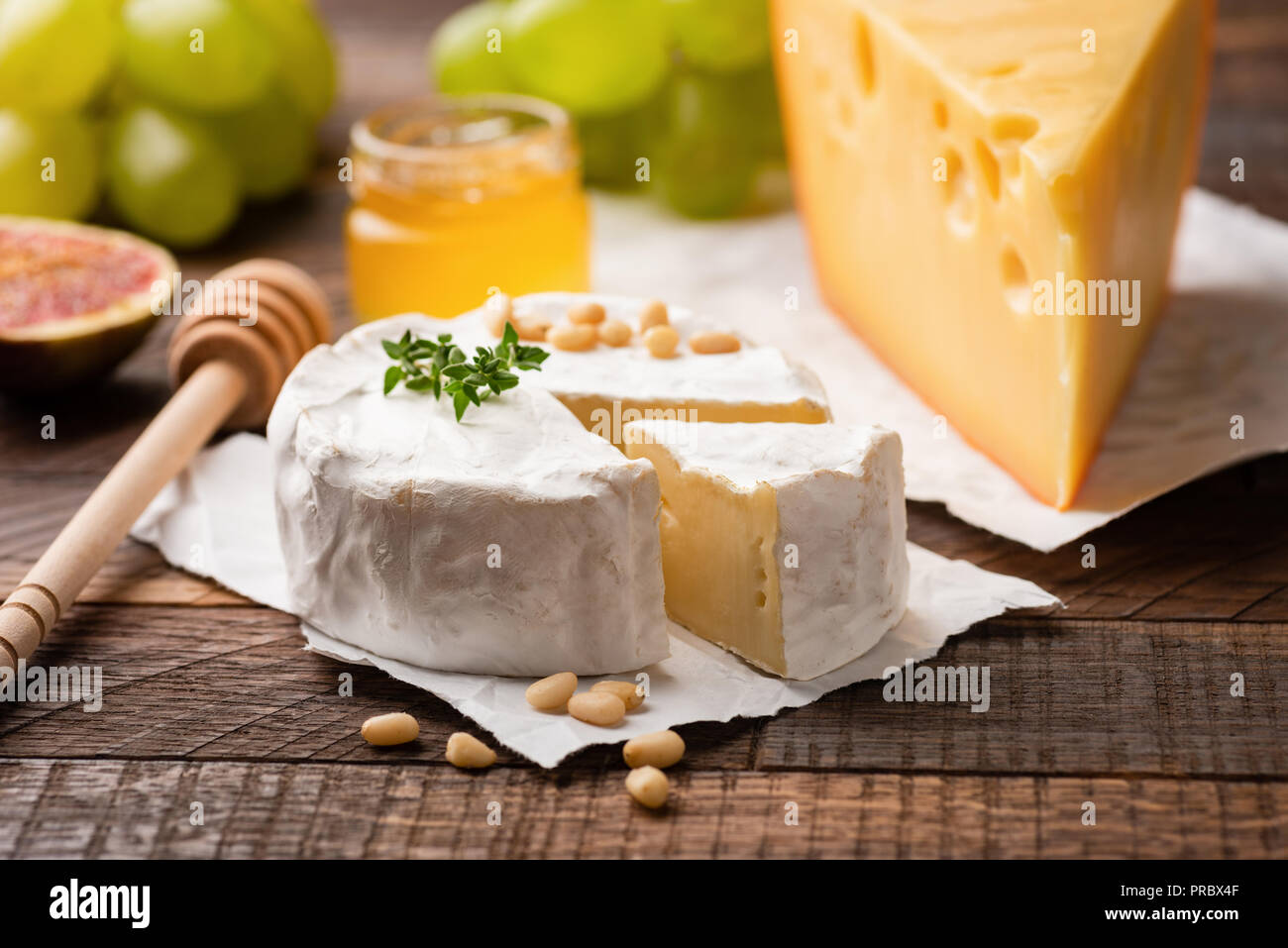 Il piatto di formaggi con brie, camembert maasdam formaggi e frutta verde uva, fichi, pinoli e timo. Primo piano. Antipasto Gourmet piastra Foto Stock