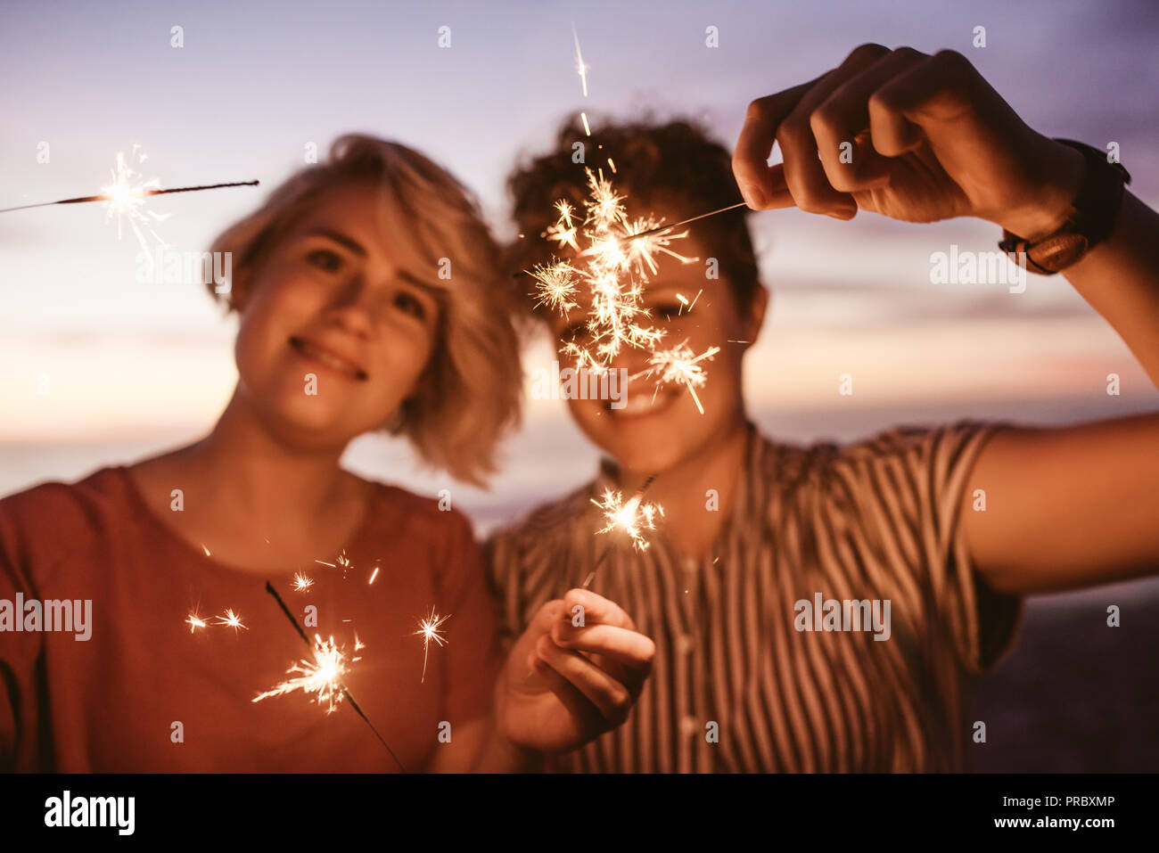 Gli amici si divertono con botti sulla spiaggia al tramonto Foto Stock
