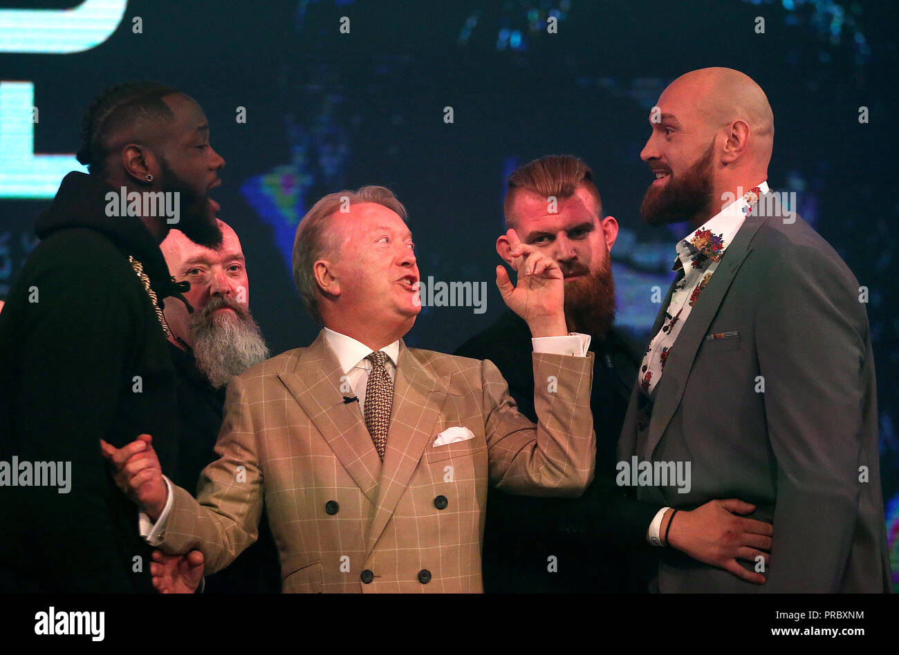 Deontay Wilder (sinistra) e Tyson Fury (destra) reagiscono come promotore Frank Warren (centro) li tiene separati nel corso di una conferenza stampa a BT Sport Studio, Londra. Foto Stock