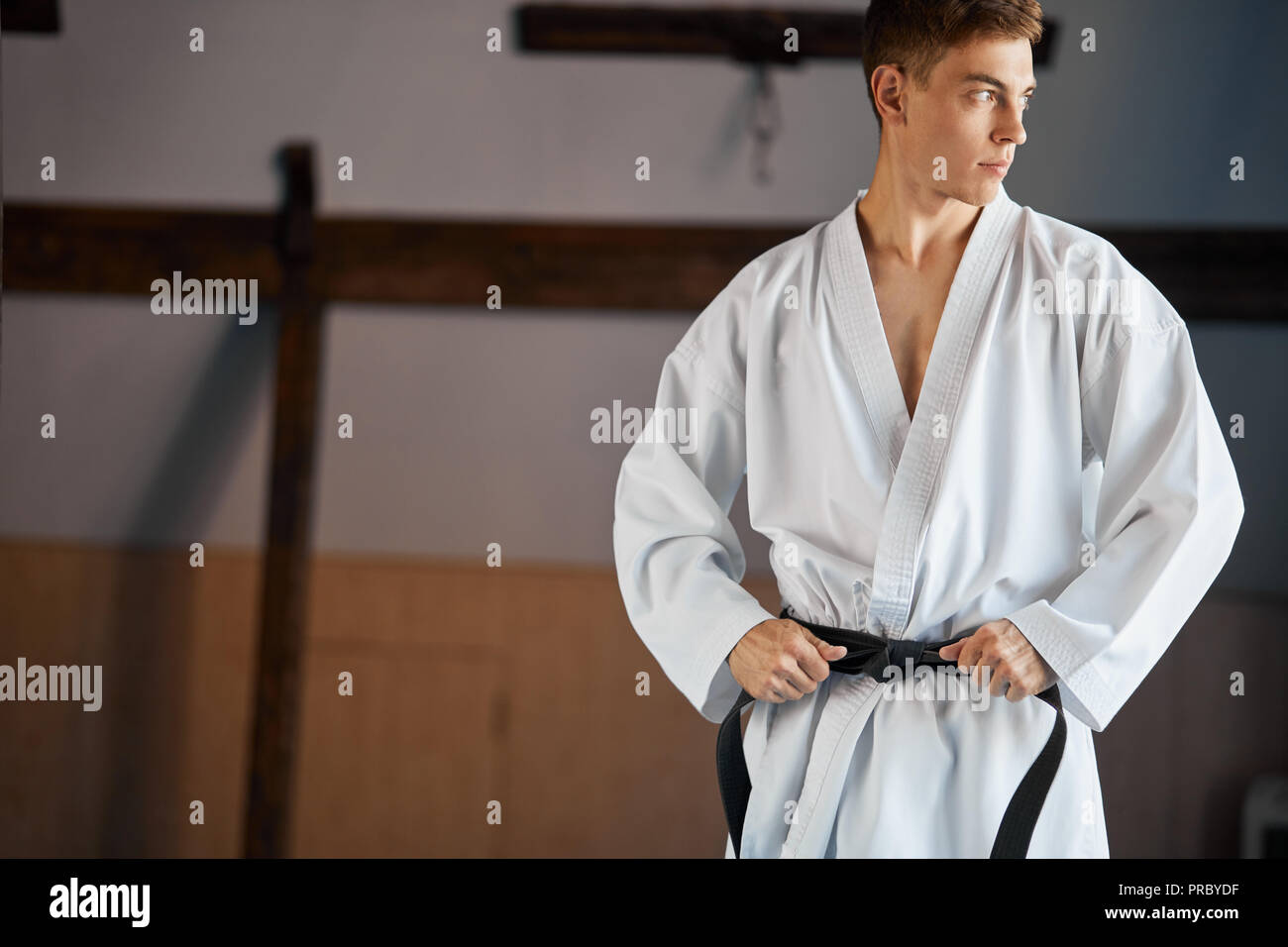 Le mani di serrare la cintura nera sull'uomo vestito di kimono Foto Stock