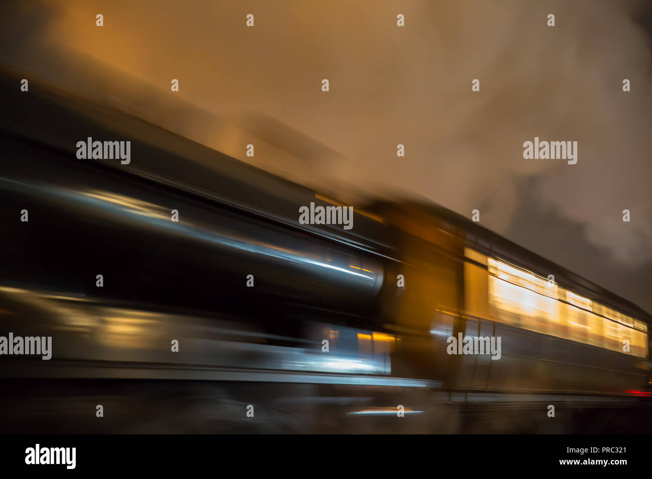 Vista spettacolare e ad angolo basso del treno a vapore del Regno Unito in movimento, locomotiva di notte. Esposizione lunga, movimento, sfocatura del movimento; concetto ad alta velocità, velocità di movimento. Foto Stock
