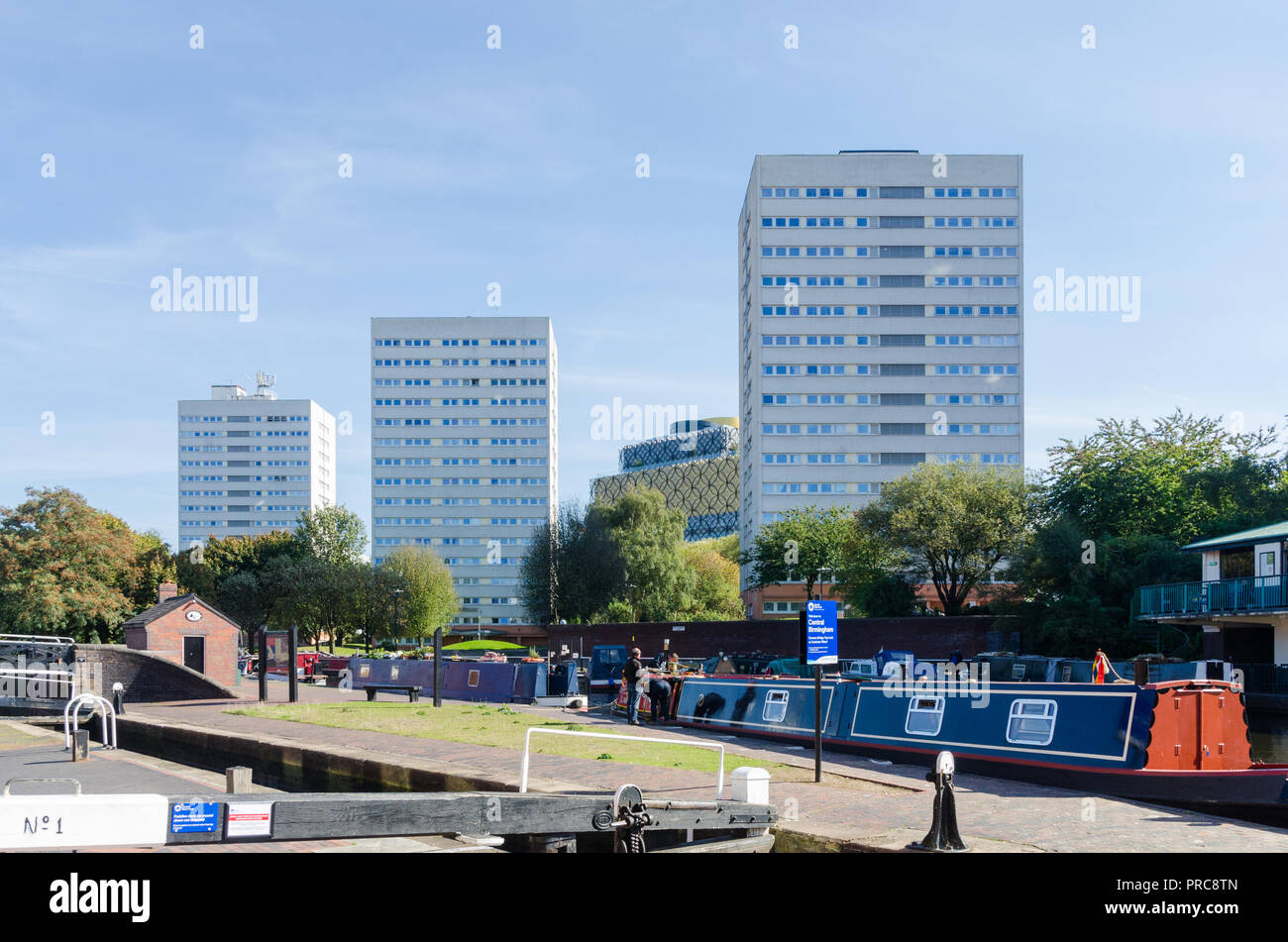 Elevato aumento di blocchi di ex consiglio appartamenti vicino al canale nel centro di Birmingham con la Biblioteca di Birmingham in background Foto Stock