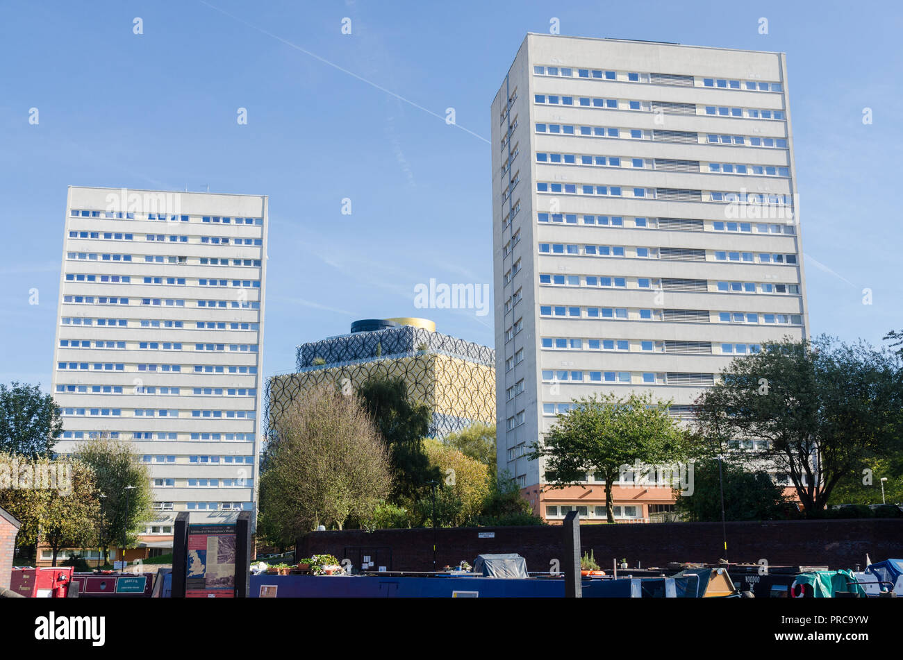 Elevato aumento di blocchi di ex consiglio appartamenti vicino al canale nel centro di Birmingham con la Biblioteca di Birmingham in background Foto Stock