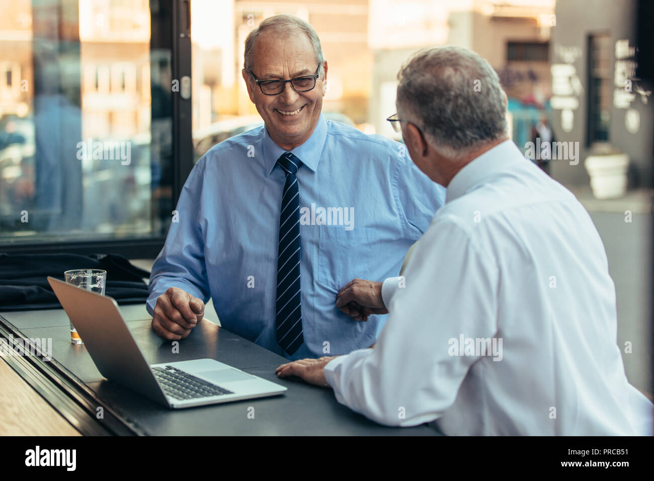 Imprenditori matura al cafe contatore con laptop a discutere di lavoro. Professionisti aziendali di conversazione informale presso il cafe dopo il lavoro. Foto Stock