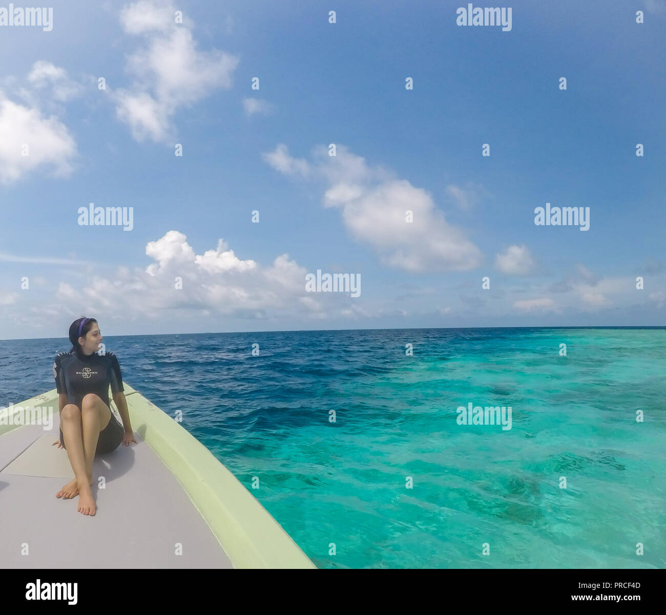 Ragazza seduta in un scuba diving suit nelle Maldive che si affacciano sull'oceano Foto Stock