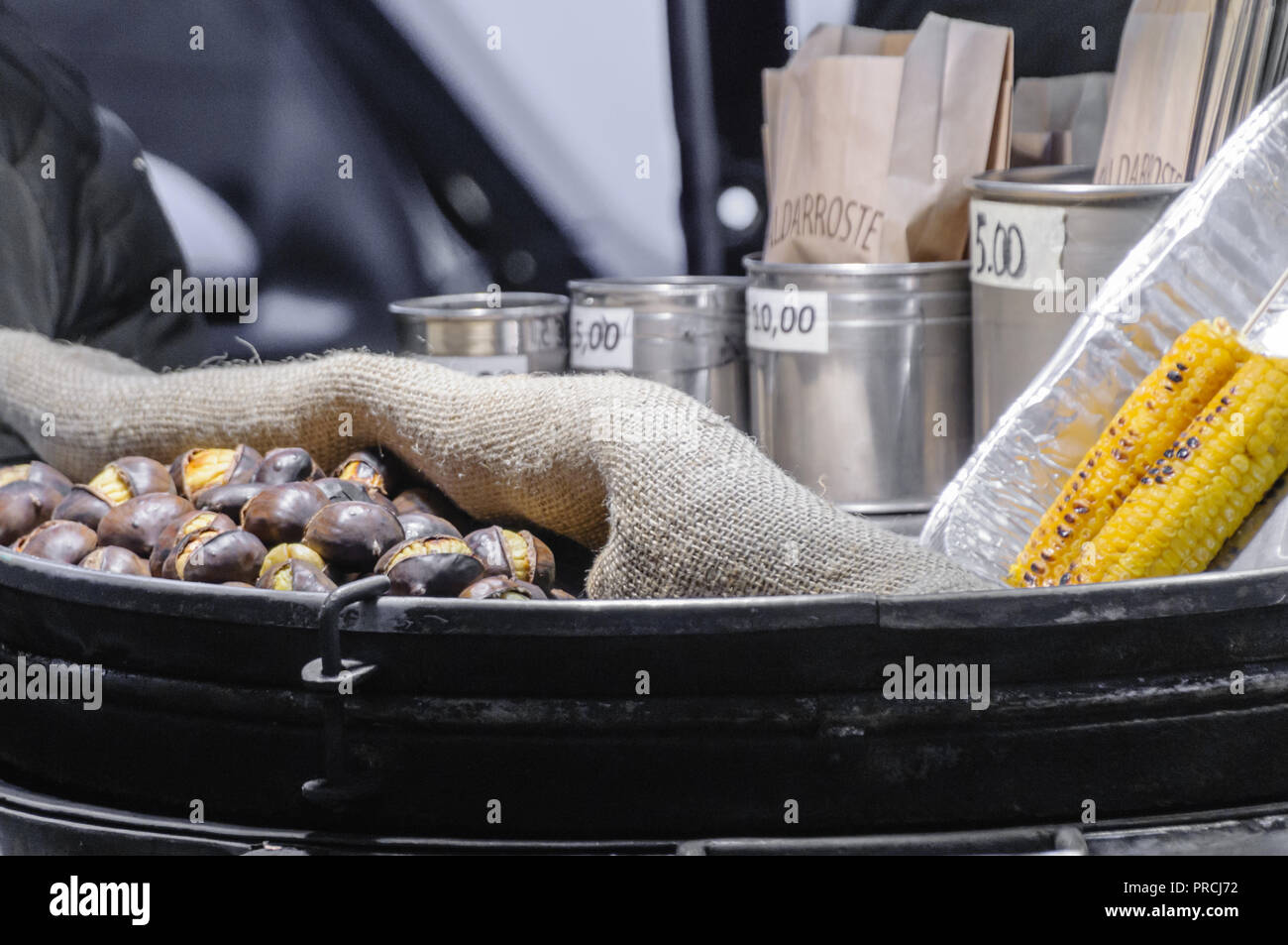 Arrosto di castagne e la pannocchia in vendita presso un venditore ambulante di carrello. Foto Stock