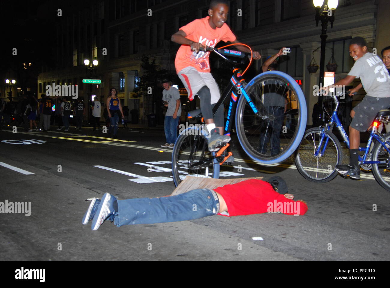 Una persona che si trova sulla strada mentre un altro salta su di lui con una bici durante una celebrazione per il Golden State Warriors campionato NBA, Foto Stock