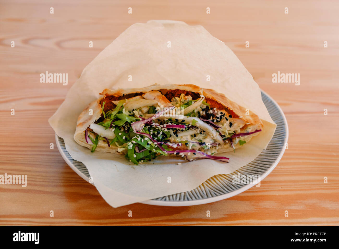 Close-up sandwich shaurma involtini di pollo in pita con verdure fresche servita su piastra in un fast food cafe Foto Stock