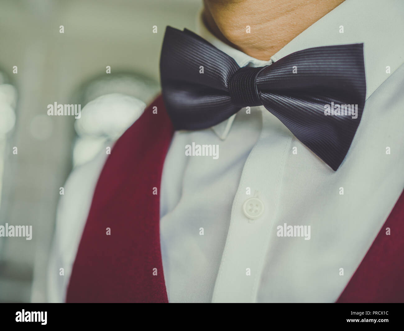 Close-up nero farfallino su bianco camicia pulita con il rosso o il giubbotto di borgogna. Foto Stock
