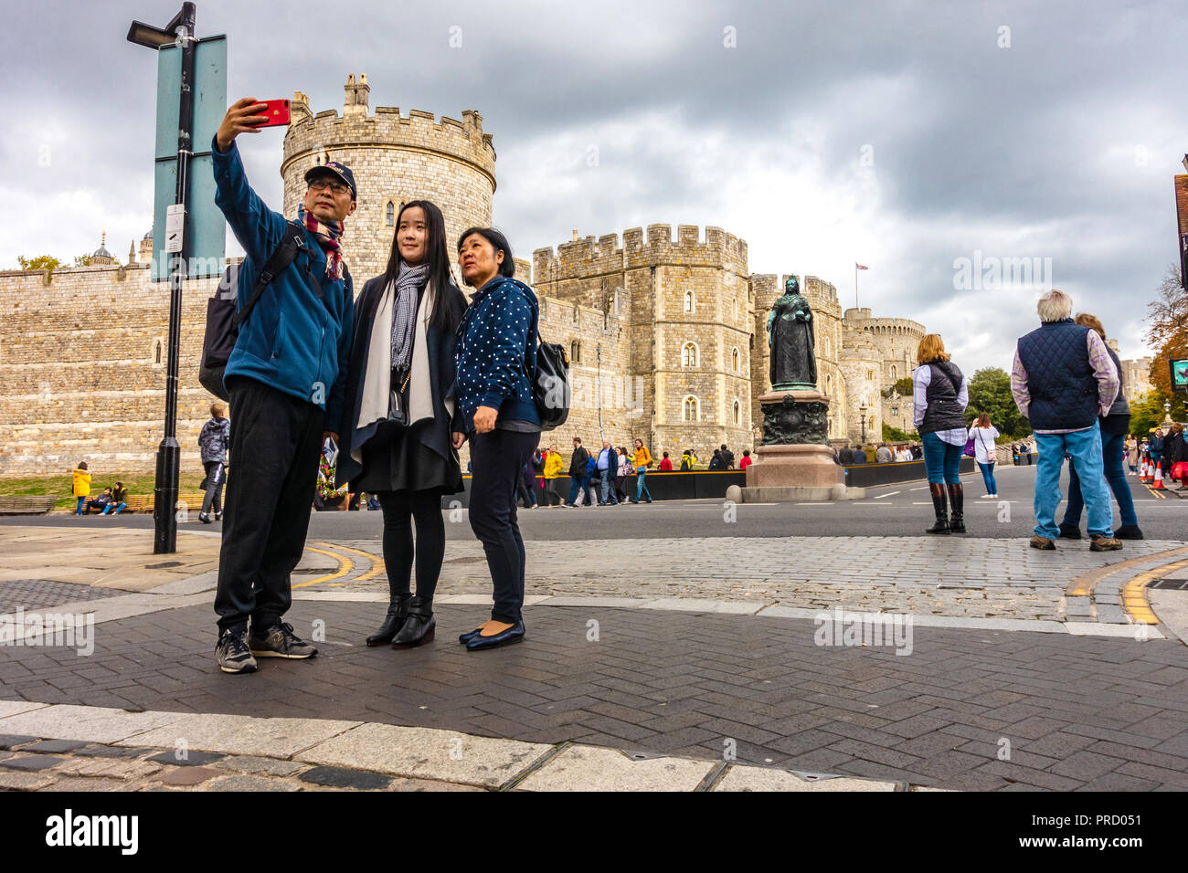 Un turista famiglia asiatica posano per una selfie scattate con un telefono cellulare nella parte anteriore del Castello di Windsor in Windsor, Regno Unito Foto Stock