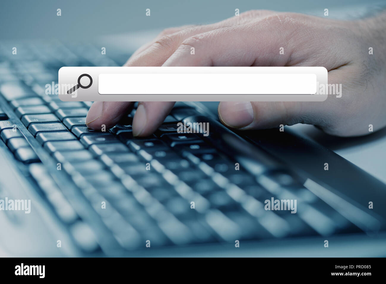 Man mano digitando su una tastiera con il tasto di ricerca Foto Stock