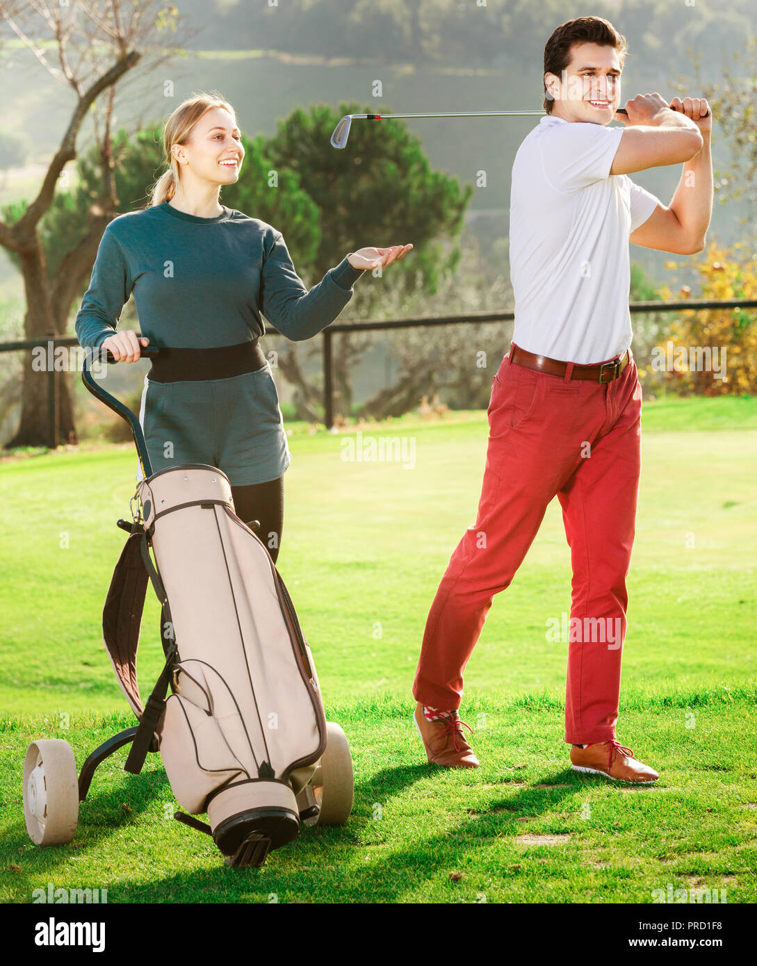 Allenatore sportivo mostra femmina e giovane giocatore di golf per giocare a golf e colpire la sfera correttamente. Foto Stock
