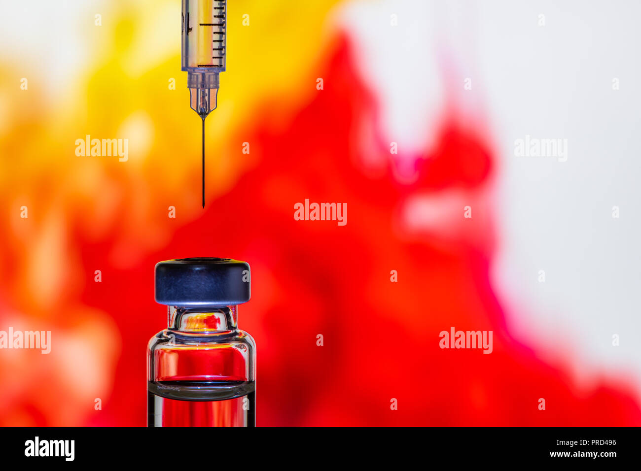 Una siringa con l'ago il punto al flaconcino di vaccino sul colorato sfondo astratto Foto Stock