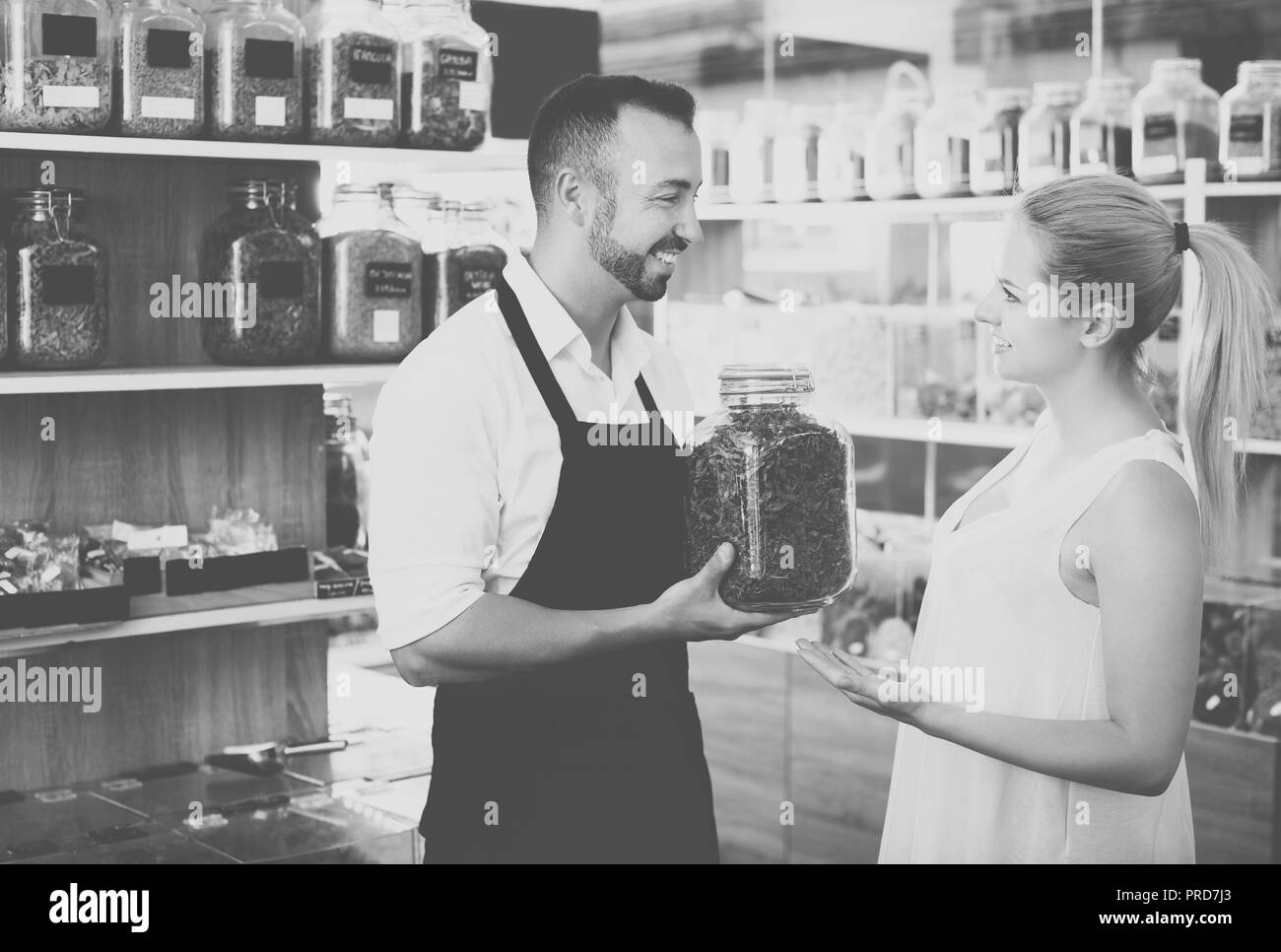 Maschio positivo venditore avendo jar con le erbe essiccate in mani cliente consulenza Foto Stock