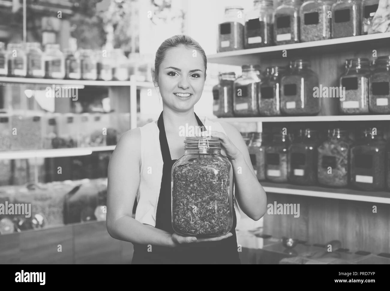 Donna adulta venditore azienda di vetro può con le erbe essiccate in organico negozio Foto Stock