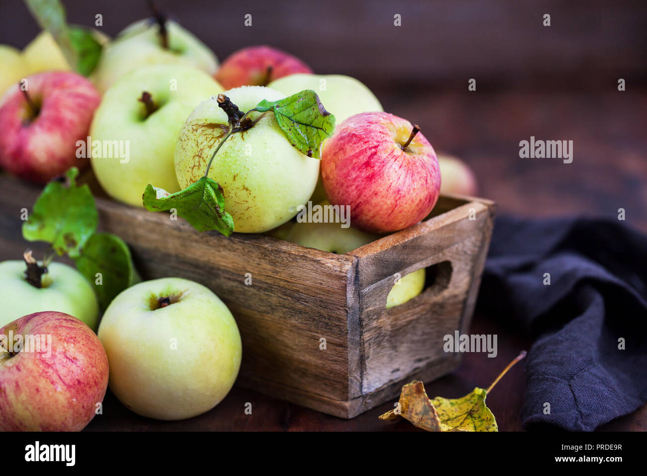 Fresche e mature mele colorate in una scatola di legno su sfondo rustico Foto Stock