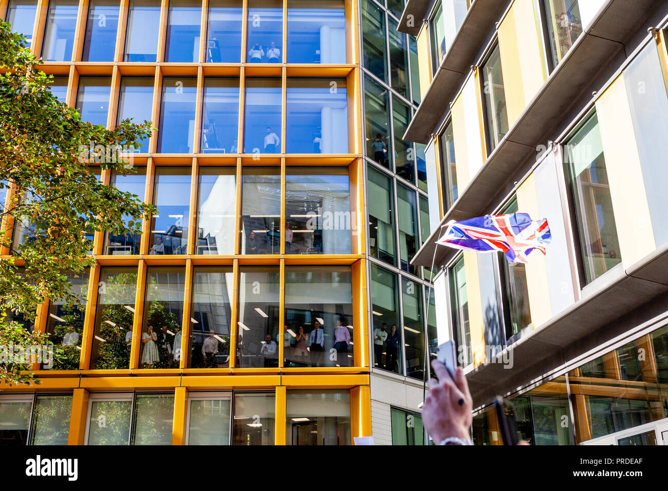 Ufficio lavoratori guarda come rumoroso sostenitori dell'ala destra attivista Tommy Robinson raccogliere al di fuori del centro di Corte penale (Old Bailey), London, Regno Unito Foto Stock