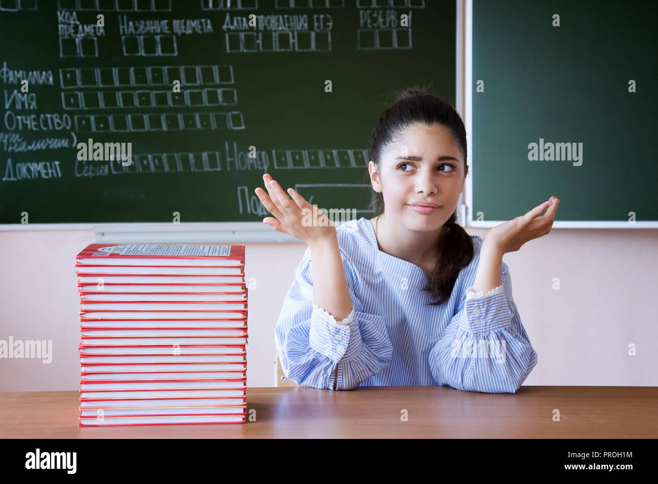 Supdrised ragazza in bicchieri siede contro la lavagna con il riempimento del campione in esame n scuola russa Foto Stock