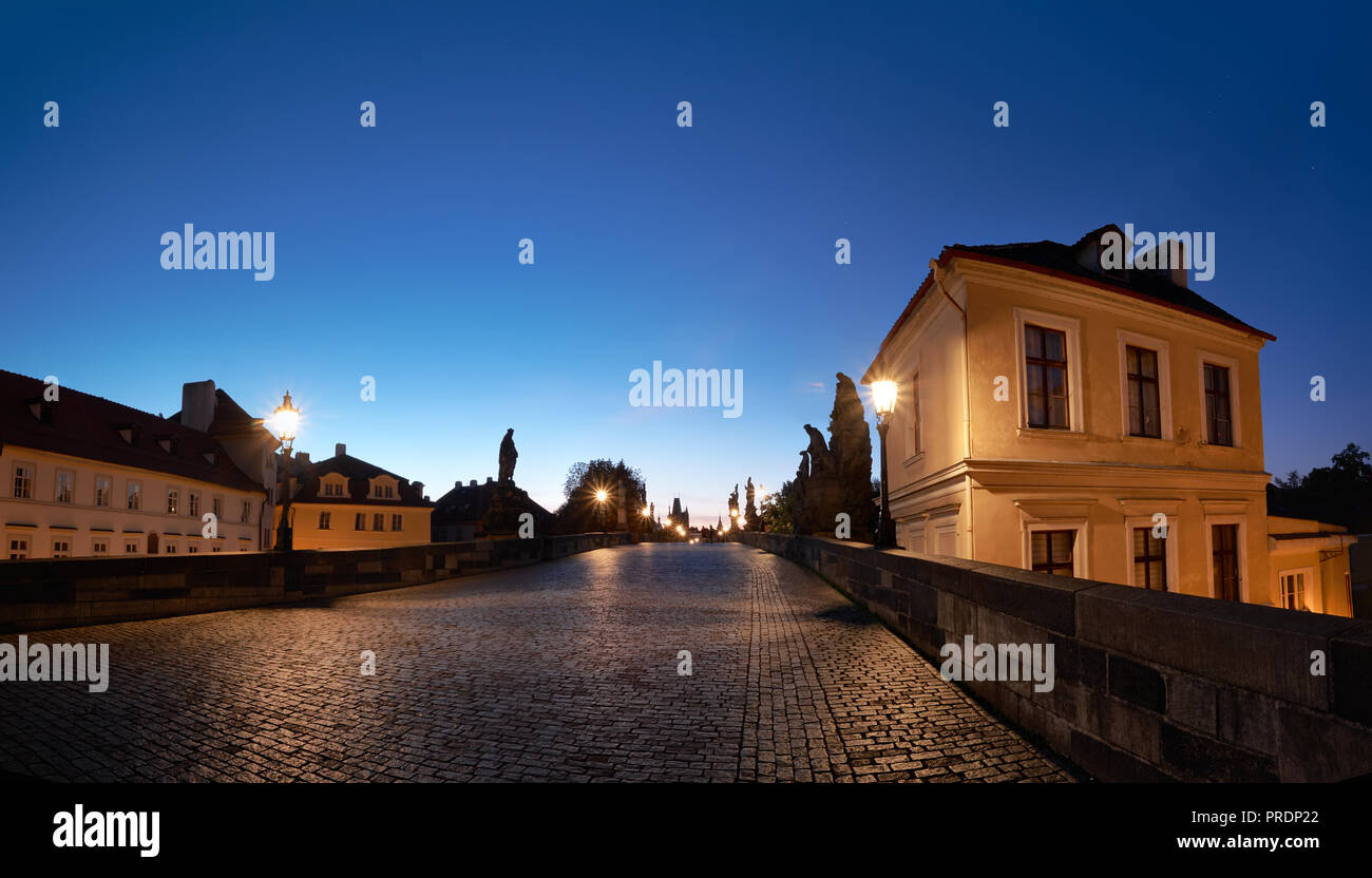 Praga di notte illuminata di case storiche e Charles Bridge dopo la pioggia con piastrelle bagnate Foto Stock
