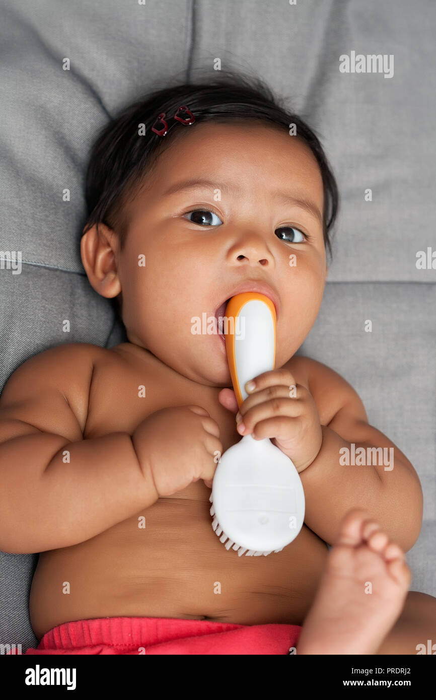 7 mese baby istintivamente esplora oggetto da mettere nella sua bocca utilizzando una griffa di presa simili a Foto Stock