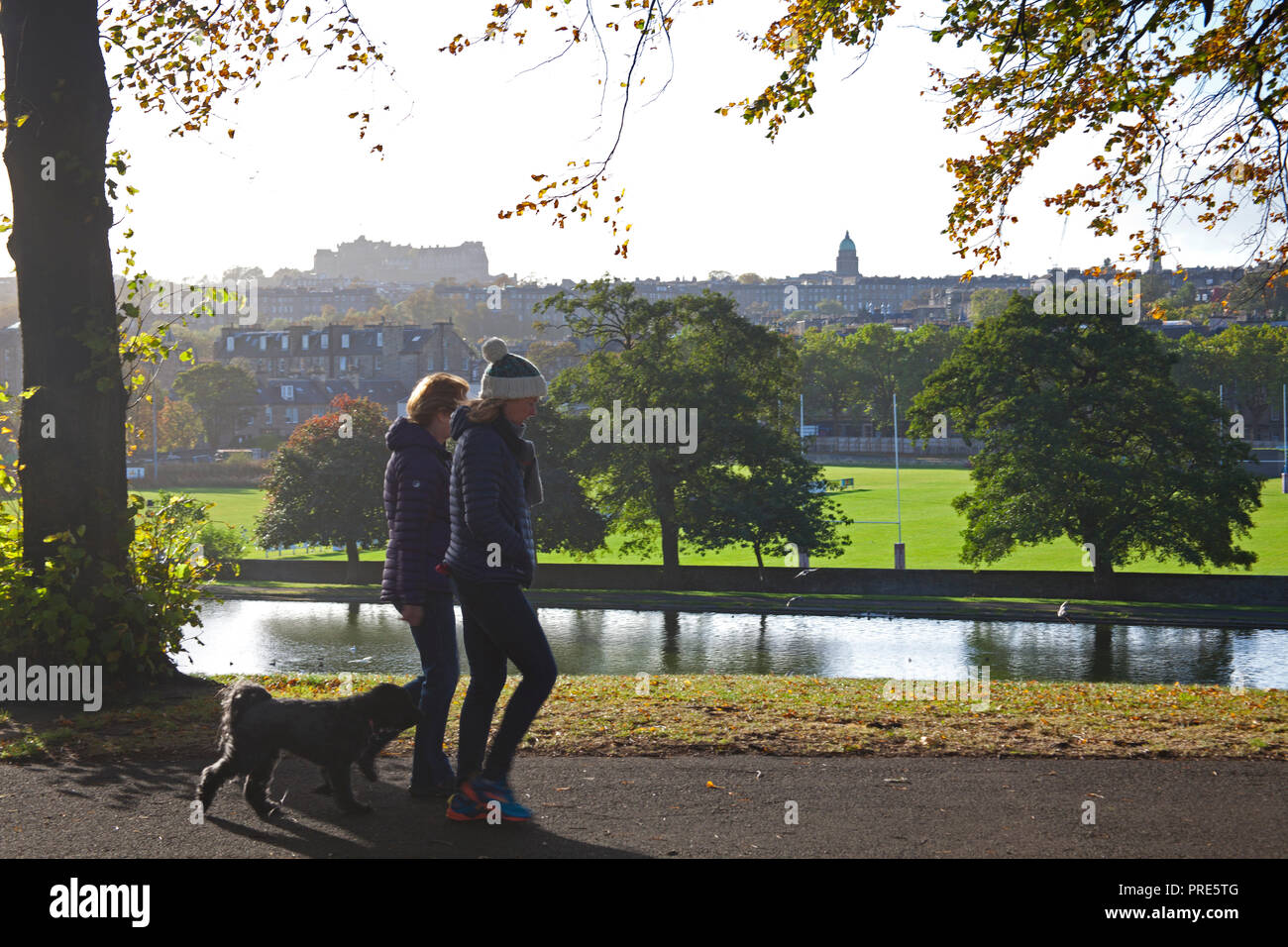 Edinburgh, Inverleith Park, Scotland, Regno Unito. 2 Ottobre, 2018. Meteo, soleggiato con 11 gradi e di 19 km/h venti con raffiche di 28km/h da nord, la gente avvolta fino contro il freddo mentre passeggiate nel parco, i colori dell'autunno sono arrivati prima del solito ma le foglie sono soffiando fuori i rami a causa di recenti venti di tempesta. Foto Stock