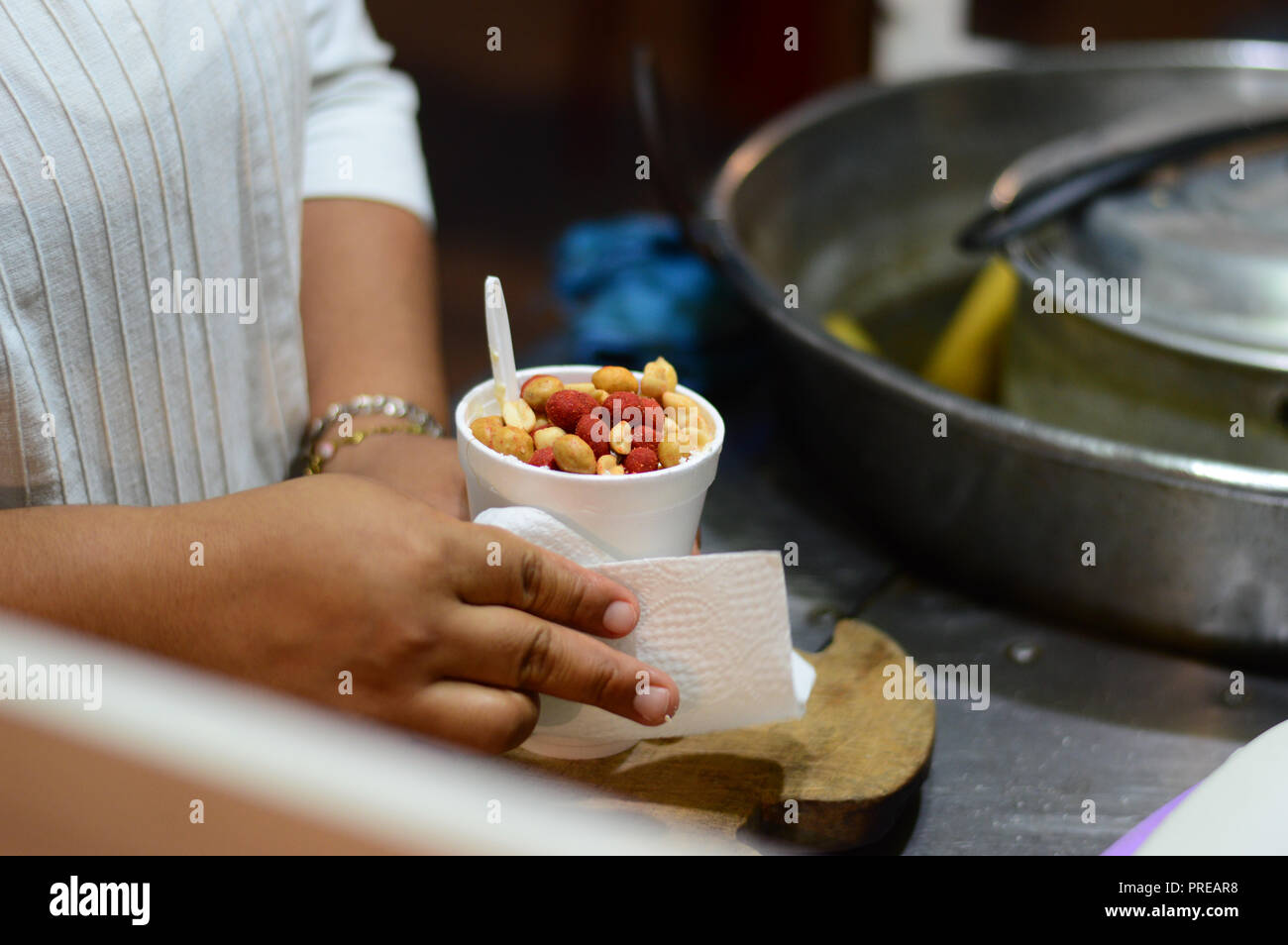 Esquites, messicano street cibo costituito di mais in una tazza con diversi condimenti, arachidi in questo caso. Foto Stock